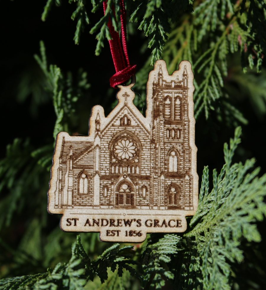 A custom wooden church ornament of St. Andrew's Grace Church hanging on evergreen branches with a burgundy velvet ribbon